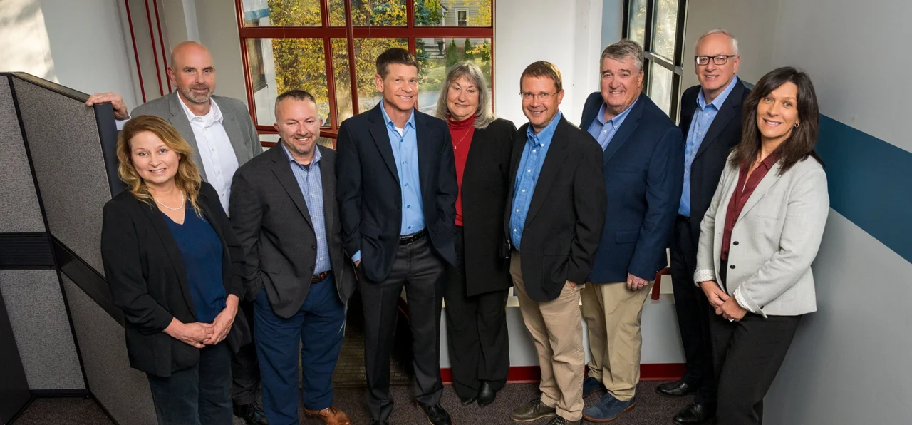 Schneider Resources team members gathered in an office workspace near a stairwell and large windows.